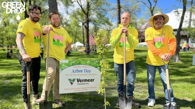 The Green Drop team, consisting of four men in yellow shirts, stands next to a tree, highlighting their unity and purpose.